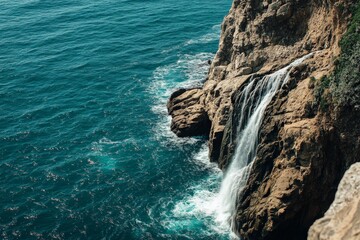 A rugged coastal landscape features a dramatic waterfall cascading into the sea, illustrating nature's raw power and beauty with a serene oceanic backdrop.