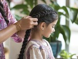 A mother braiding her daughter's hair while sharing stories during a cherished family gathering.