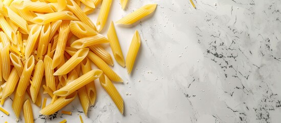 Canvas Print - Top down view of raw penne pasta on a marble board against a white textured background suitable for adding text or images. Copy space image. Place for adding text and design