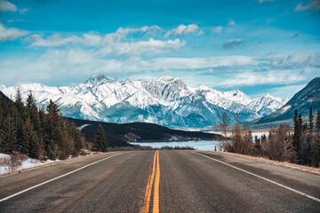 road trip with on highway road with snow covered rocky mountains in winter at kootenay plains area, 