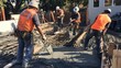 © sirisakboakaew - Site workers handling concrete pouring into formwork for beam construction