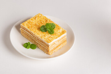 Creamy vanilla biscuit cake with cream or puff pastry  on a white plate isolated on a white background