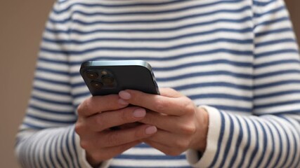 A close-up of hands holding a smartphone at home or work. Woman using smartphone pressing fingerers, reading social media internet, typing text or shopping online.