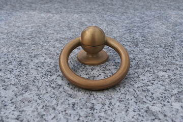 A copper ring rests on a smooth surface of gray marble. The warm, reddish copper contrasts sharply with the cool, veined patterns of the stone, while soft light highlights the ring's shine.