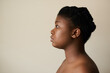 © mavoimages - Young African woman with perfect skin standing sideways on a light background