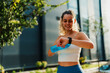 © DusanJelicic - Fitness-focused woman checking her smart watch while holding a water bottle, enjoying an outdoor setting.