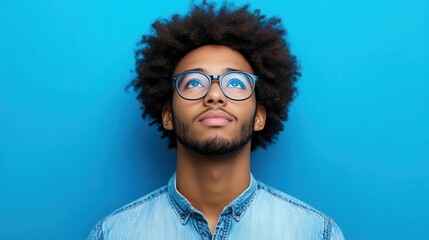 Wall Mural - A man with glasses and a beard is looking up at the sky. Concept of curiosity and contemplation, as the man seems to be pondering something or simply enjoying the view