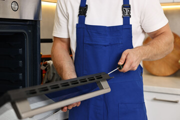 Sticker - Repairman with screwdriver fixing oven indoors, closeup