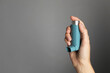© New Africa - Woman holding asthma inhaler on grey background, closeup. Space for text
