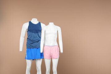 Female and male mannequins with stylish sportswear on beige background, space for text