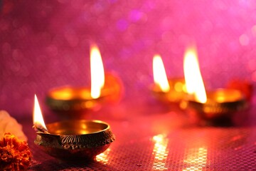 Poster - Diwali celebration. Diya lamps and beautiful flowers on color background, closeup. Space for text