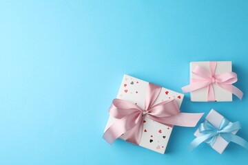 Canvas Print - Gift boxes with bows on light blue background, flat lay. Space for text