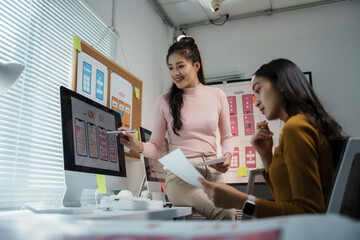 Two female designers discussing about user interface design for mobile application on computer in office