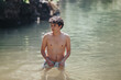 © qunica.com - A young man stands waist-deep in a serene pond, enjoying a relaxing swim surrounded by nature. The sunny setting provides a peaceful atmosphere.