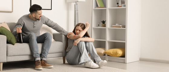 Wall Mural - Bruised young woman and her drunk husband at home. Domestic violence concept