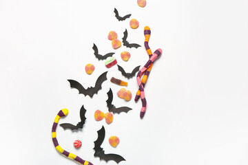 Sticker - Composition with sweet jelly candies and paper bats on light background