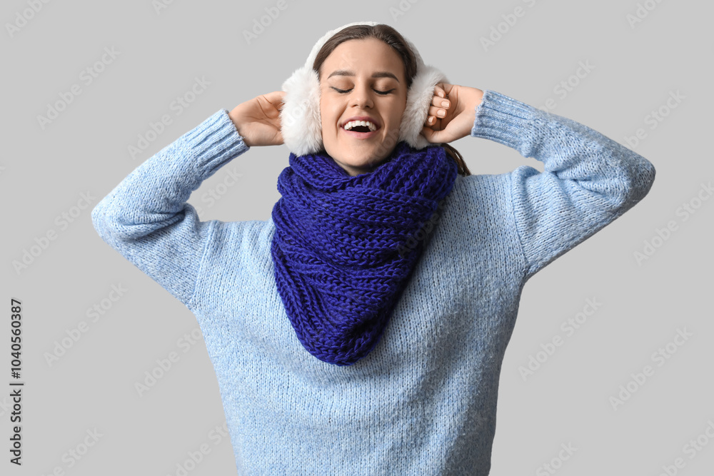 Happy young woman in winter clothes on light background