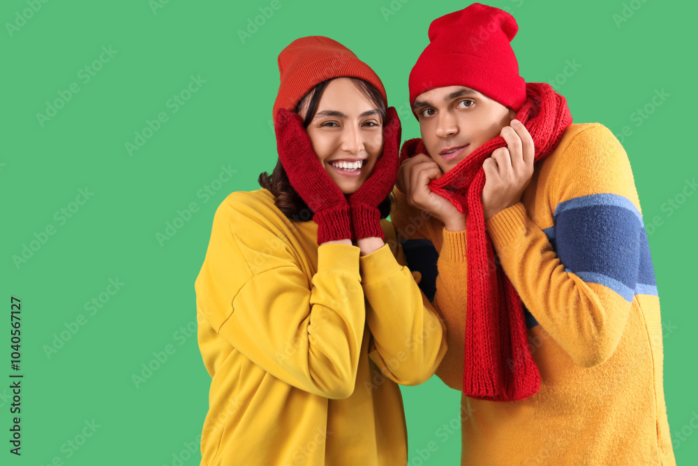 Happy young couple in warm clothes on green background