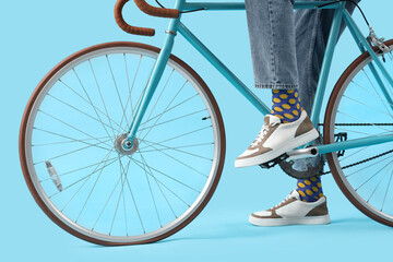 Canvas Print - Young man in sneakers with bicycle on blue background