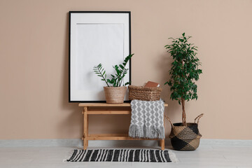 Wall Mural - Bench with basket, houseplants and frame on beige wall in room