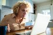 © Geber86 - Mature woman working on laptop on kitchen desk at home