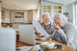 © Marko Geber - Senior couple stressed over financial documents at kitchen table