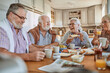 © Marko Geber - Diverse senior friends eating breakfast together at kitchen table