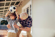 © Marko Geber - Grandfather and son bonding while playing with a soccer ball on house porch