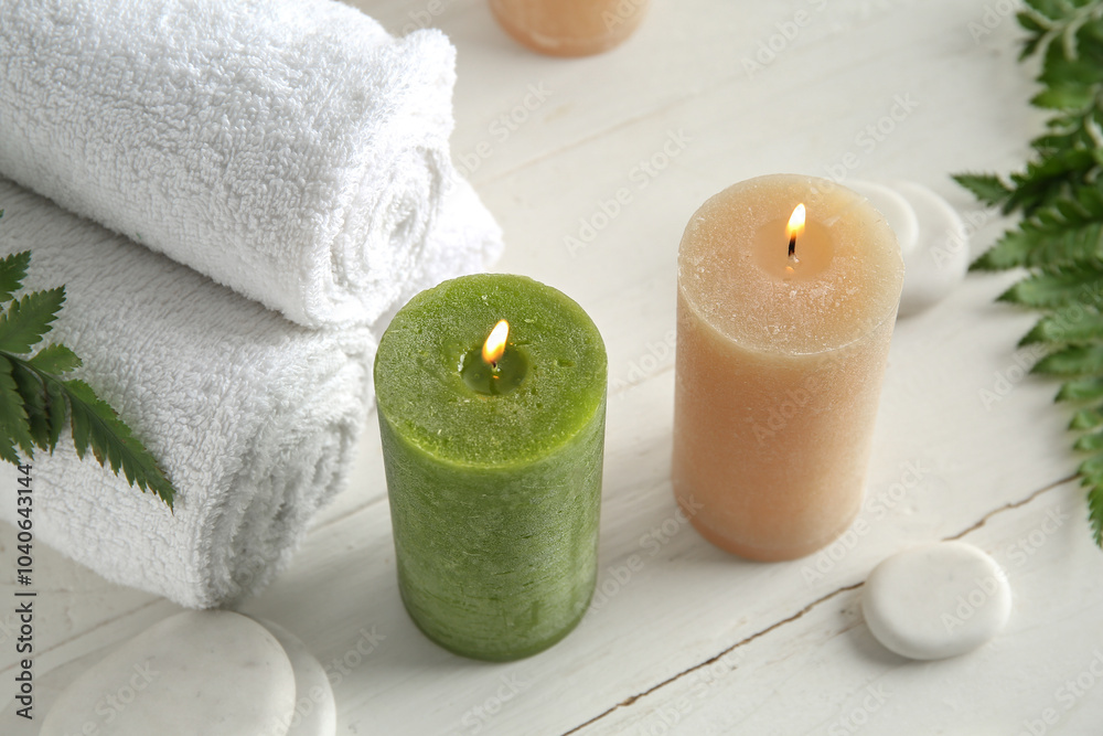 Candles, spa stones and towels on light background