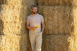 © Volodymyr - Portrait man farmer harvester on harvested hay. Farmer keeping hay bales to stock. Farmer In Wheat Field After Harvest Examining Hay. Crops After Harvesting. Farm Lifestyle. Barn, Hay Rolled Bales.