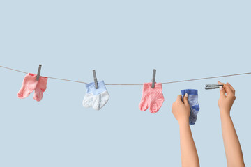 Poster - Female hands with baby socks hanging on rope against blue background