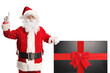 © Ljupco Smokovski - Santa claus pointing and leaning on a tv with red ribbon