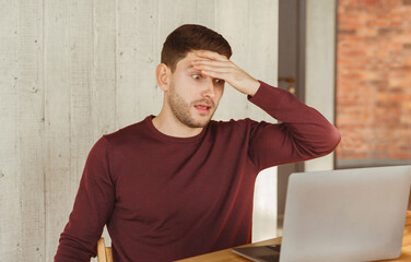 Poster - Overworked Employee Looking In Shock At Laptop Touching Forehead Sitting In Office. Selective Focus
