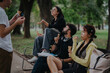 © qunica.com - A group of students and a professor take a relaxing ice cream break in the park. They are seated on a bench, chatting and enjoying the sunny day together.