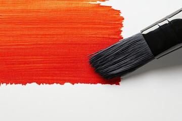 Close-up of a paintbrush applying smooth red paint on a white surface