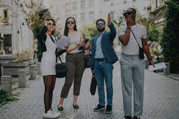 Canvas Print - Diverse group of business professionals standing on urban sidewalk, engaged in conversation and consulting papers. Teamwork, collaboration, and decision-making in a modern city setting.