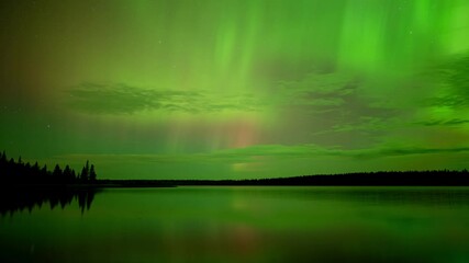 Wall Mural - time lapse green flickering and rolling aurora in night sky reflecting in a calm lake