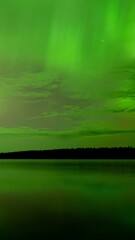 Wall Mural - time lapse night sky with green flickering and rolling aurora reflecting in a calm lake