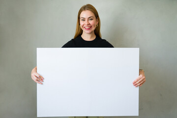 Happy woman displaying a blank whiteboard with ample space for your message or design