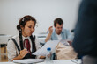 © qunica.com - Students actively participate in a classroom session as a professor provides assistance. The scene captures a collaborative learning environment emphasizing individualized support and engagement in