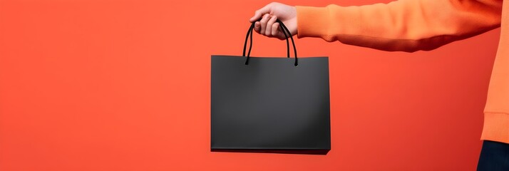 Man holding black shopping bag on red background. Online shopping concept. Black Friday, 11.11 Single Day, Cyber Monday. Autumn sale and discount advertising banner, poster, flyer with copy space