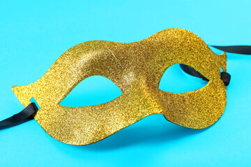 Sticker - One golden carnival mask on light blue background, closeup