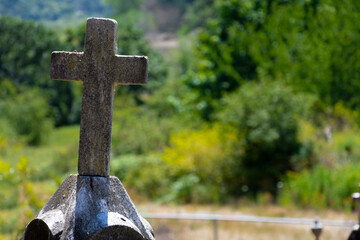 An image of a carved stone cemetery cross on top of a stone monument. 