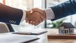 © Luxetify - Two businessmen shake hands over a model house and paperwork.