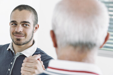 Young employee shaking hands with senior colleague in the office