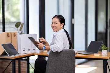 Asian Business woman using calculator and laptop for doing math finance on an office desk, tax, report, accounting, statistics, and analytical research concept
