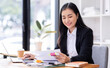 © David - Business asian woman Reviewing Documents, business woman's hands meticulously reviewing a stack of documents, highlighting the details and precision of her work.