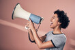 © peopleimages.com - Studio, protest and woman with megaphone for voice, leadership or communication for message. Courage, female person or activist with vocal for opinion, speaker or freedom of speech by pink background
