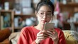 © Luxetify - Young woman wearing glasses looking at her phone with a thoughtful expression.