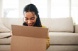 © peopleimages.com - Home, woman or happy with box for opening, shipment or delivery product in living room with smile. House, female person or excited with package for surprise, present or cardboard for parcel in lounge